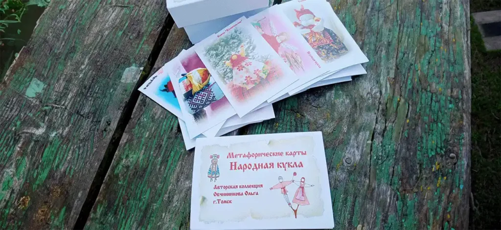 Колода метафорических карт «Народная кукла» психолога Ольги Овчинниковой разложена на деревянном столе.